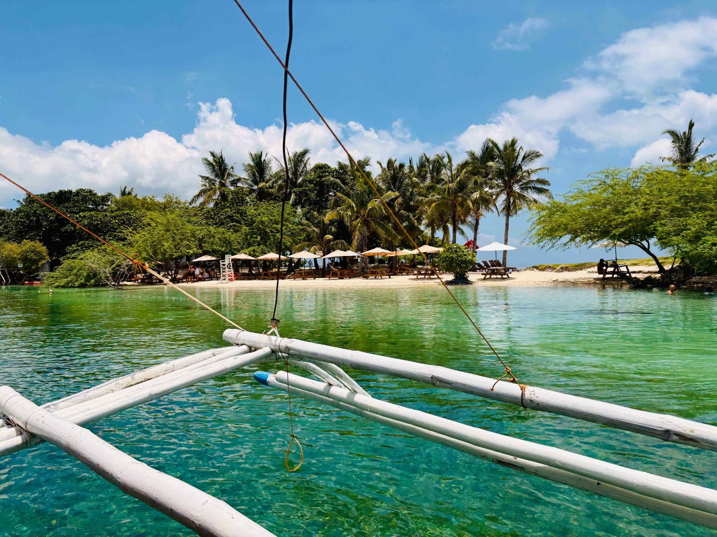 View from an outrigger boat approaching the sandy shore and palm trees of Baigad Lagoon in Bantayan, Cebu.