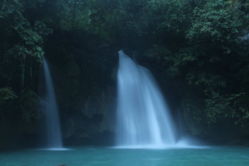Waterfalls cascading into a deep turquoise natural pool at Kawasan Falls in Badian, Cebu
