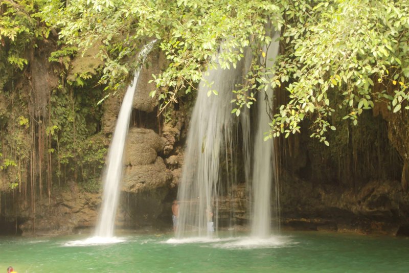 Gentle multi-tier waterfall streams flowing over mossy rock formations into a clear basin