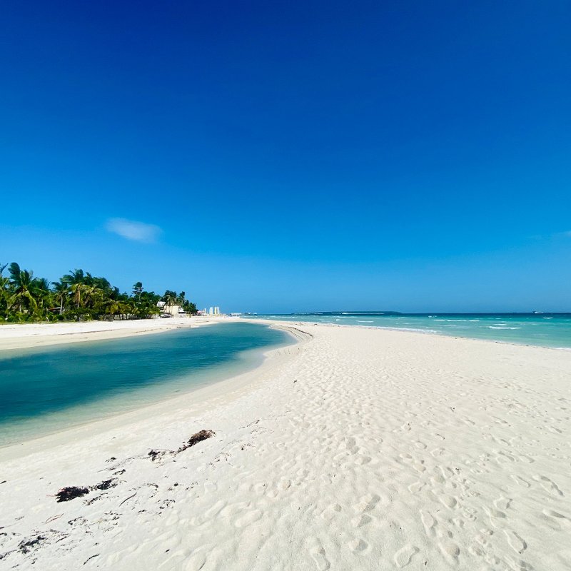 White sand beach and turquoise water at Kota Beach, Bantayan Island under a clear blue sky.