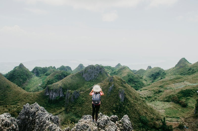 Hiker standing on a rocky peak overlooking the unique limestone hills of Osmeña Peak.