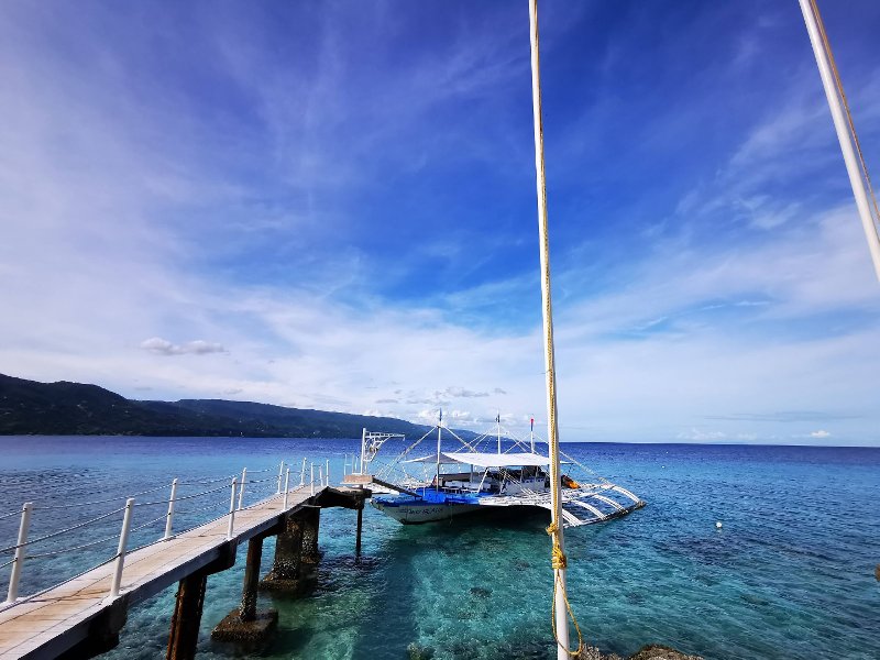 Blue waters and a small outrigger boat docked at Sumilon Island