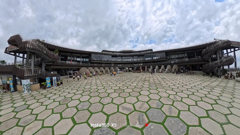 Ground-level wide view of the open-air central plaza at Tops Cebu, showing hexagonal paved stone flooring surrounded by a multi-tiered circular building.