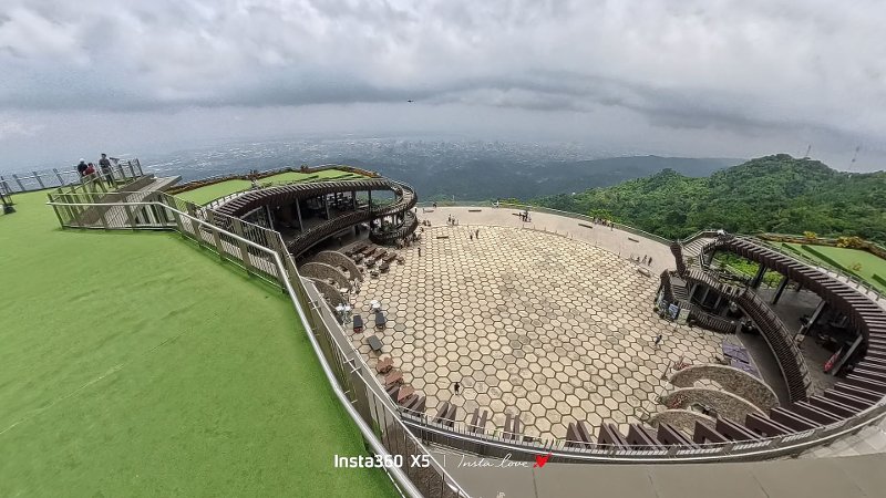 High-angle panoramic view of the Tops Cebu complex overlooking the outdoor plaza, green terraced walkways, and sweeping views of Cebu City under overcast skies.