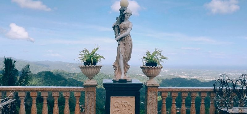 세부 부사이의 푸른 산줄기를 배경으로 선 여신 조각상.