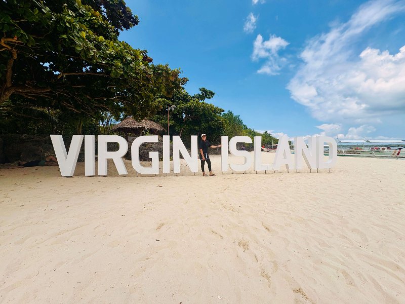 Large white block letters spelling "VIRGIN ISLAND" on a white sand beach in Bantayan, Cebu.